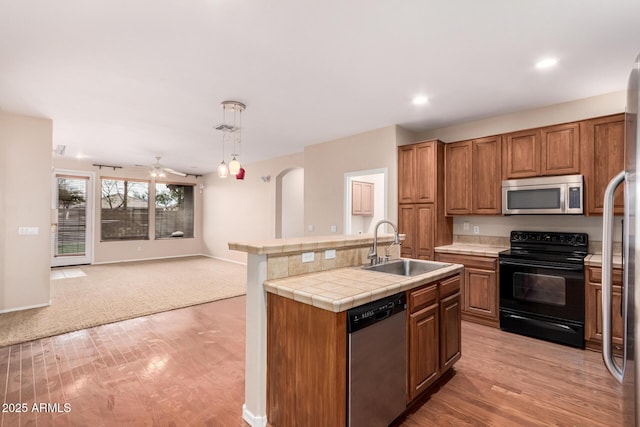 kitchen with arched walkways, appliances with stainless steel finishes, a sink, and brown cabinets