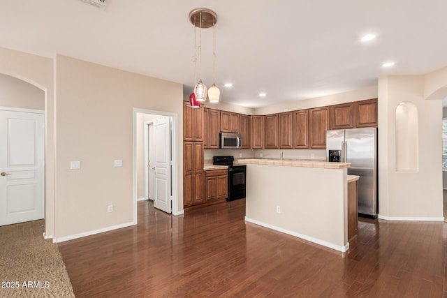 kitchen featuring appliances with stainless steel finishes, arched walkways, brown cabinetry, and light countertops