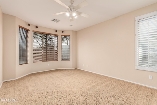 unfurnished room featuring carpet floors, visible vents, ceiling fan, and baseboards