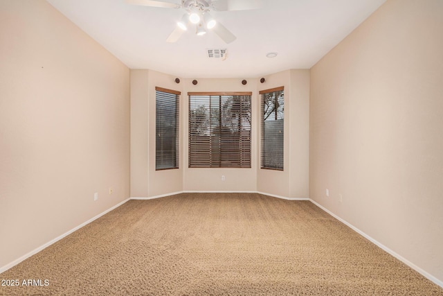 carpeted empty room with visible vents, ceiling fan, and baseboards