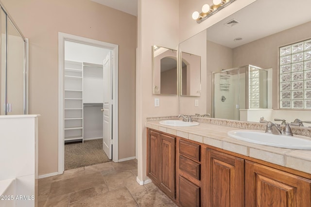 full bathroom featuring a spacious closet, a stall shower, a sink, and visible vents