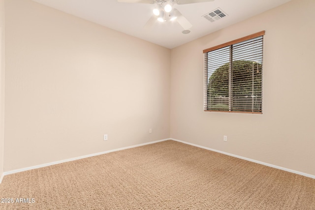 carpeted spare room featuring a ceiling fan, visible vents, and baseboards