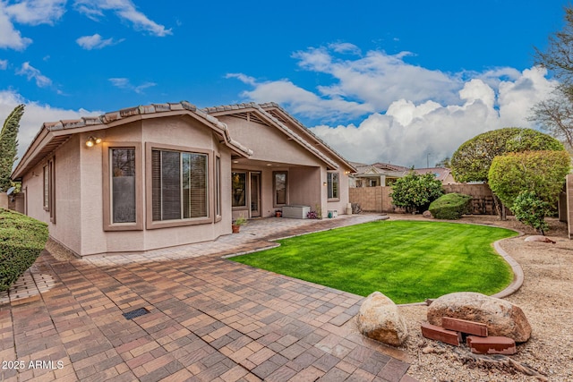 rear view of property featuring a yard, a patio area, a fenced backyard, and stucco siding