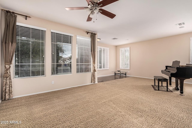 living area featuring carpet, baseboards, visible vents, and ceiling fan