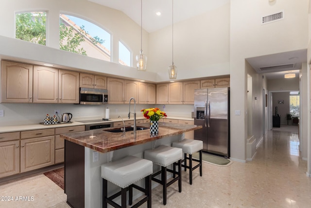 kitchen with a kitchen island with sink, a breakfast bar, sink, stainless steel appliances, and high vaulted ceiling