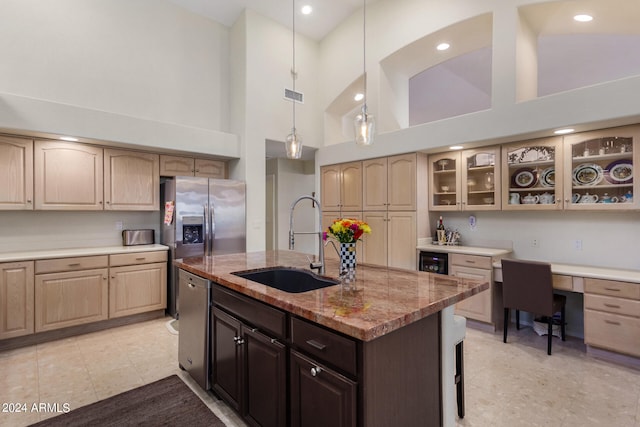 kitchen with sink, light stone counters, an island with sink, high vaulted ceiling, and appliances with stainless steel finishes