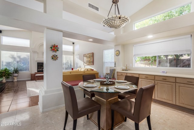 dining space featuring a towering ceiling, light tile patterned flooring, and a wealth of natural light