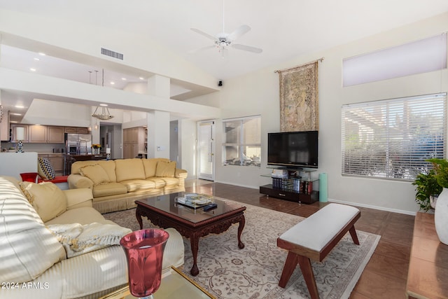 living room with ceiling fan, dark tile patterned floors, and high vaulted ceiling