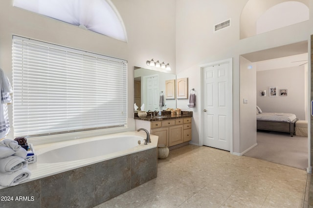 bathroom featuring vanity, tiled bath, and a towering ceiling