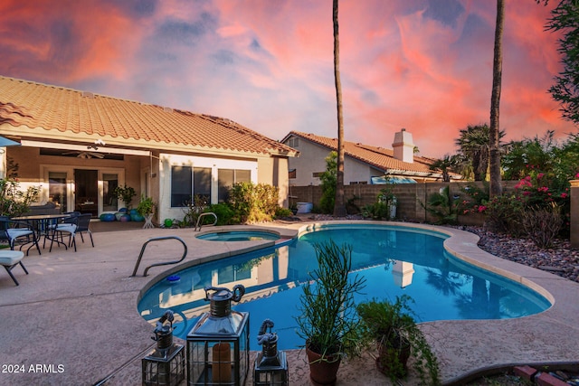 pool at dusk featuring an in ground hot tub, a patio, and ceiling fan