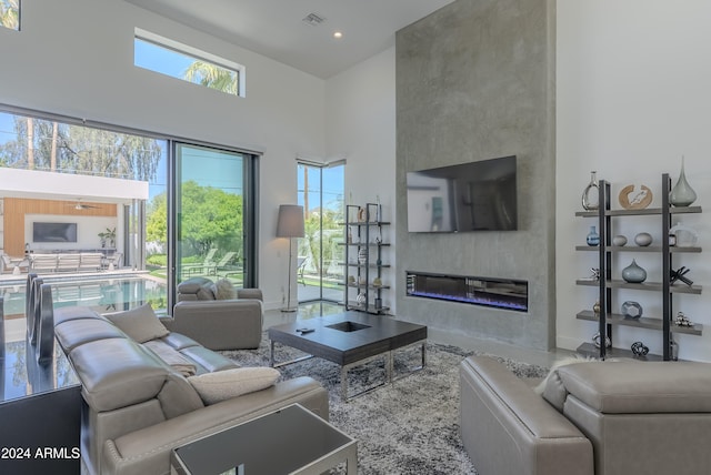 living room with a towering ceiling, a large fireplace, and plenty of natural light