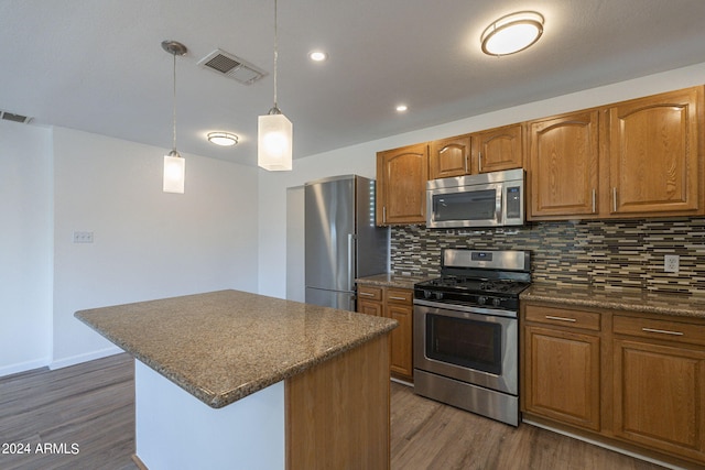 kitchen featuring a center island, dark hardwood / wood-style flooring, pendant lighting, appliances with stainless steel finishes, and backsplash