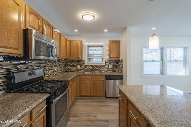 kitchen featuring brown cabinetry, dishwasher, a sink, and backsplash