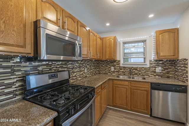 kitchen featuring dark stone counters, appliances with stainless steel finishes, hardwood / wood-style flooring, and sink