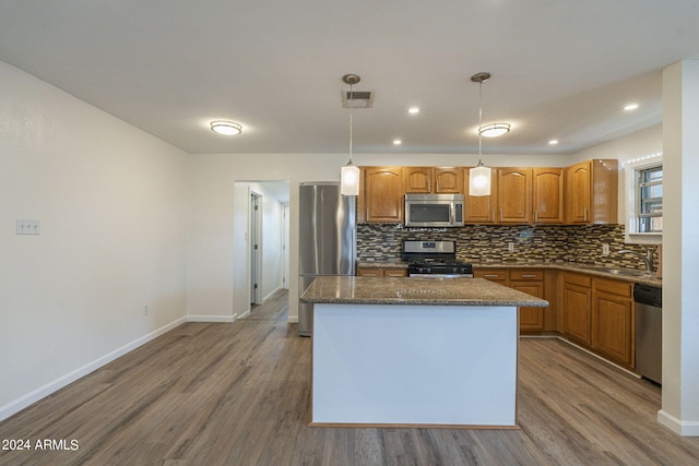 kitchen featuring tasteful backsplash, wood finished floors, a kitchen island, and stainless steel appliances