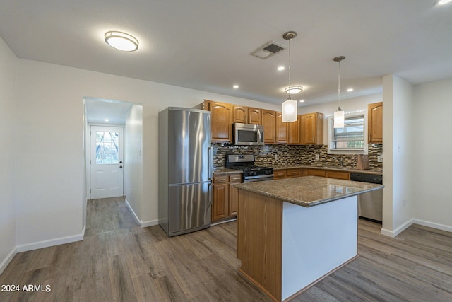 kitchen featuring pendant lighting, stainless steel appliances, a healthy amount of sunlight, and a kitchen island