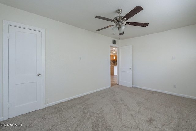carpeted empty room with visible vents, baseboards, and a ceiling fan