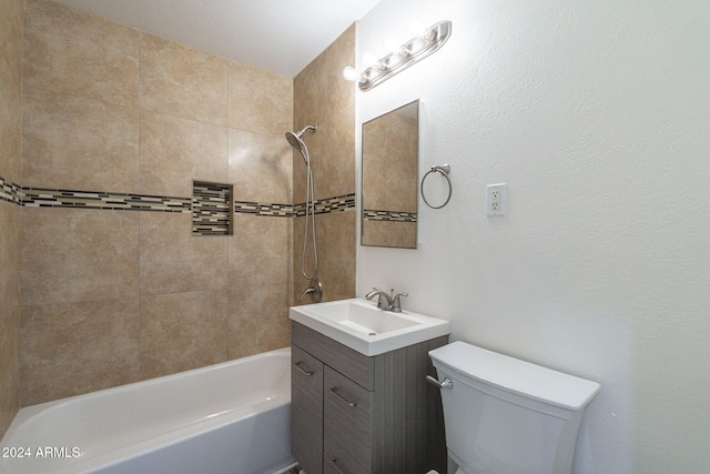 full bathroom featuring tiled shower / bath, vanity, and toilet