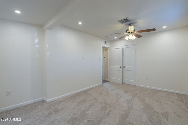 empty room featuring light colored carpet, beam ceiling, and ceiling fan