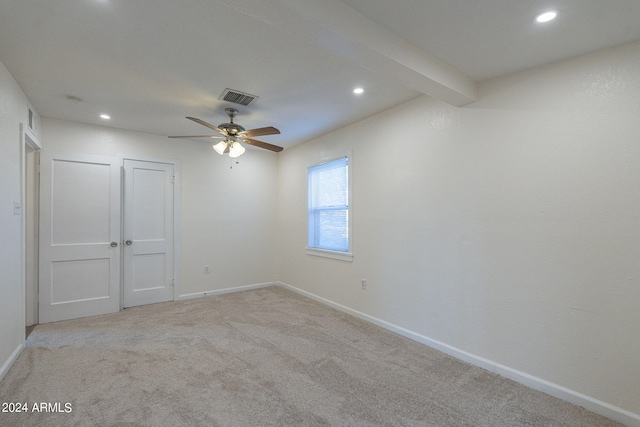 spare room with ceiling fan, beam ceiling, and light colored carpet