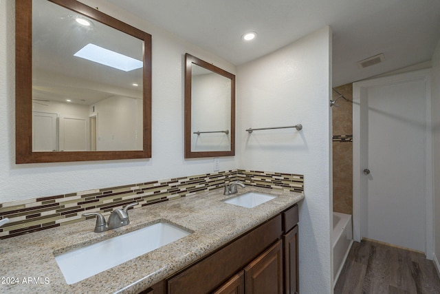 bathroom with tasteful backsplash, wood finished floors, a sink, and shower / bathing tub combination