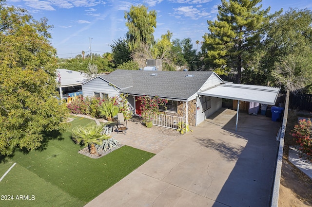 ranch-style home featuring concrete driveway, a carport, roof with shingles, a front lawn, and central AC