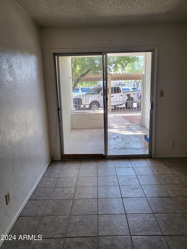 doorway to outside with a textured ceiling, a healthy amount of sunlight, and tile patterned flooring