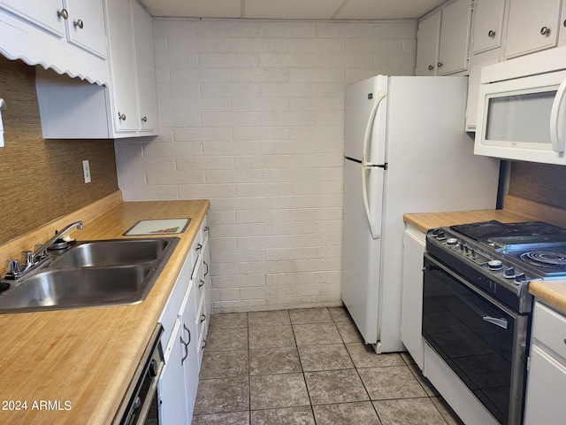 kitchen featuring range, sink, dishwashing machine, and white cabinetry