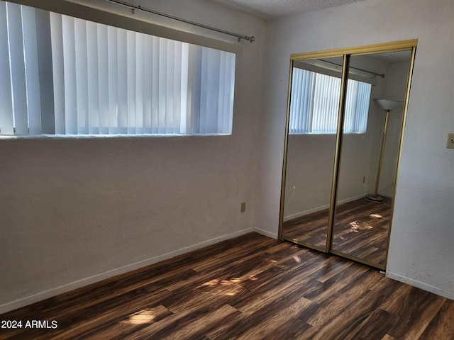 unfurnished bedroom with dark wood-type flooring, a closet, and a textured ceiling