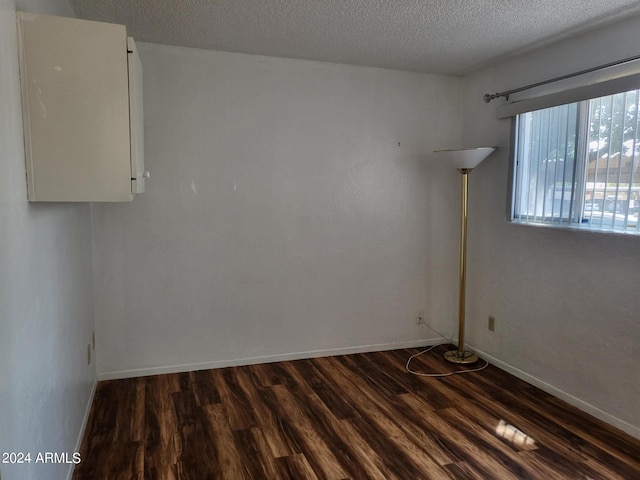 spare room featuring a textured ceiling and dark wood-type flooring