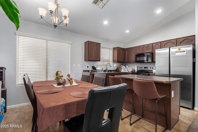 dining area featuring a notable chandelier, vaulted ceiling, a wealth of natural light, and sink