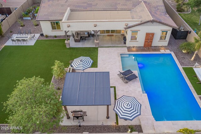 outdoor pool with a patio area, a fenced backyard, and a lawn