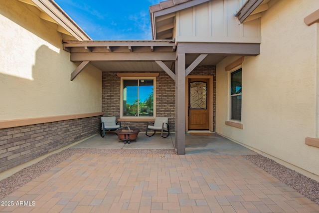 view of exterior entry featuring brick siding, stucco siding, and board and batten siding