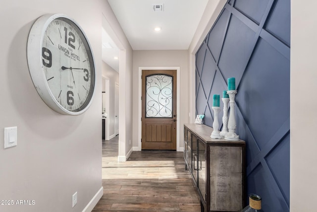 doorway to outside with dark wood-style flooring, baseboards, and visible vents