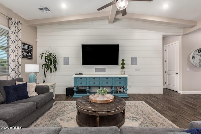 living area with visible vents, lofted ceiling with beams, a ceiling fan, dark wood-type flooring, and wood walls