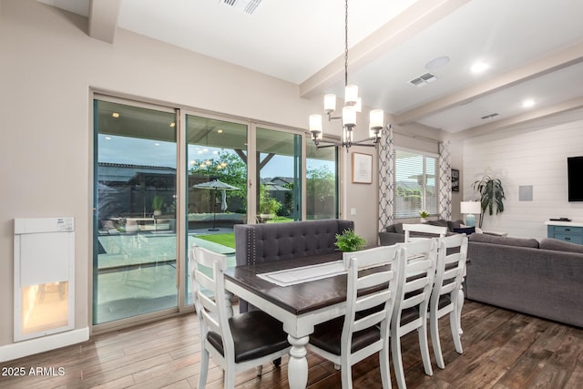 dining space featuring visible vents, a chandelier, wooden walls, beamed ceiling, and wood finished floors