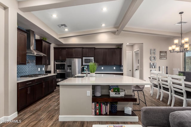 kitchen with an inviting chandelier, dark brown cabinetry, wall chimney range hood, visible vents, and stainless steel appliances