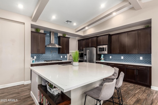 kitchen featuring visible vents, wall chimney range hood, dark brown cabinets, beam ceiling, and stainless steel appliances