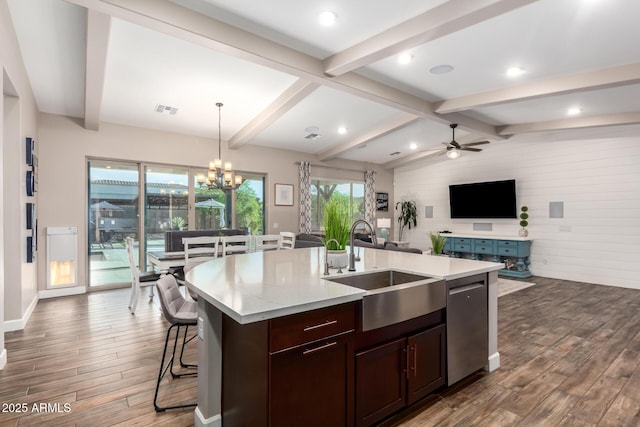 kitchen featuring dishwasher, a sink, open floor plan, wood finished floors, and ceiling fan with notable chandelier