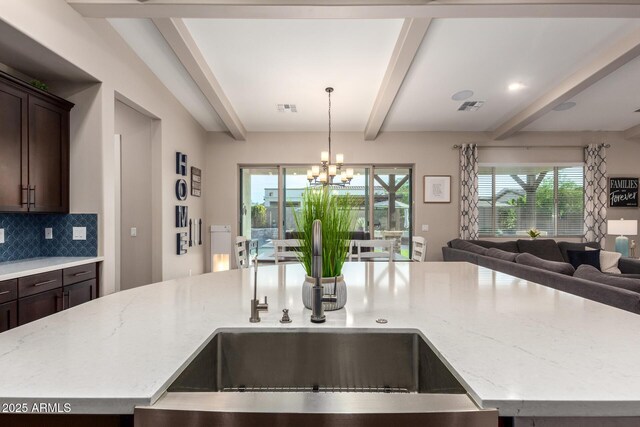 kitchen featuring light stone countertops, open floor plan, and dark brown cabinetry