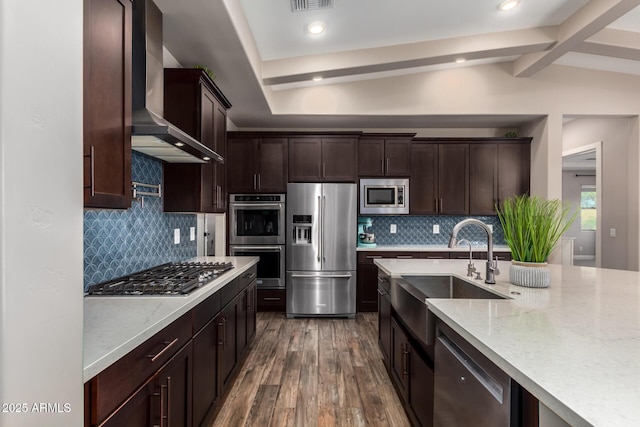 kitchen with wall chimney exhaust hood, a sink, appliances with stainless steel finishes, dark wood finished floors, and dark brown cabinets