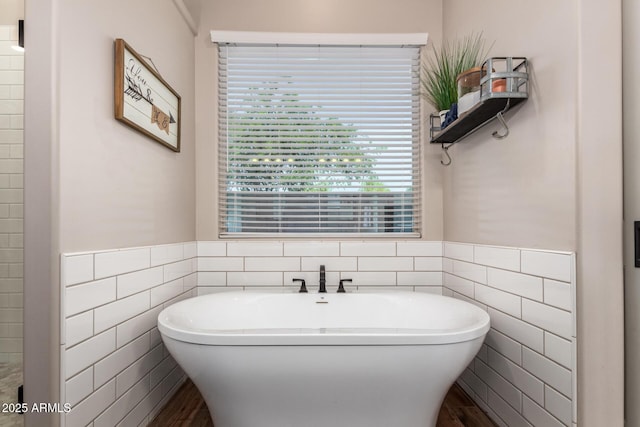 bathroom featuring a freestanding bath, wainscoting, and tile walls
