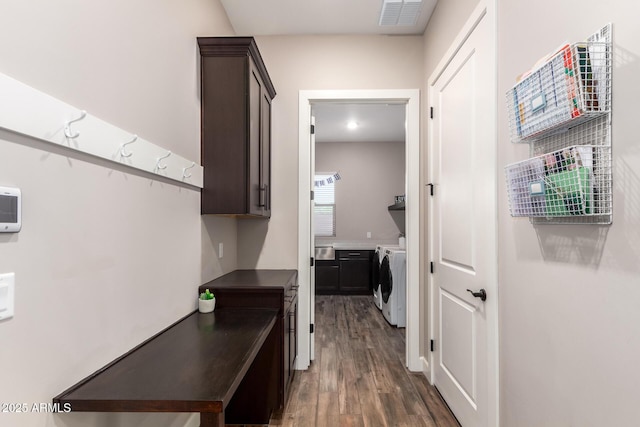hallway with dark wood-style flooring, visible vents, and washer and clothes dryer