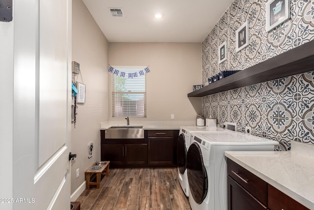 laundry area with visible vents, a sink, dark wood finished floors, cabinet space, and washing machine and dryer