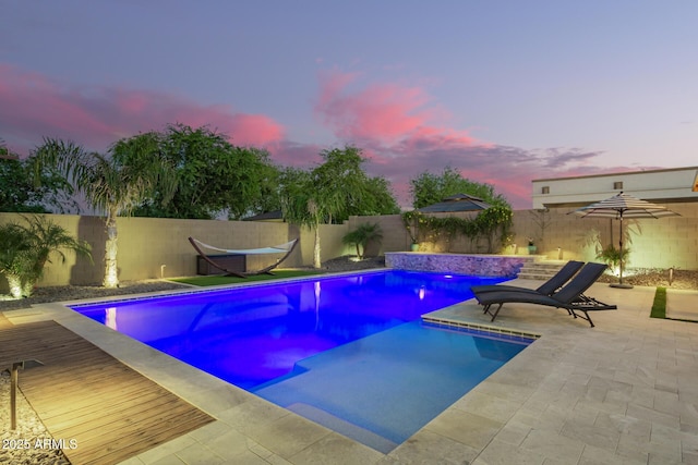 pool at dusk featuring a fenced in pool and a fenced backyard
