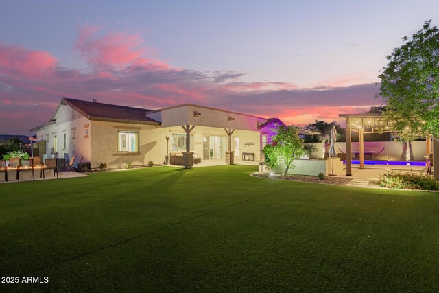 back of house with stucco siding, a lawn, a patio area, fence, and a fenced in pool