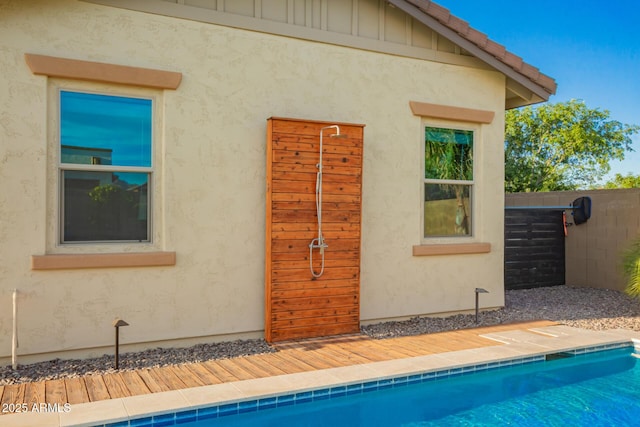 exterior space featuring a tile roof, fence, and stucco siding