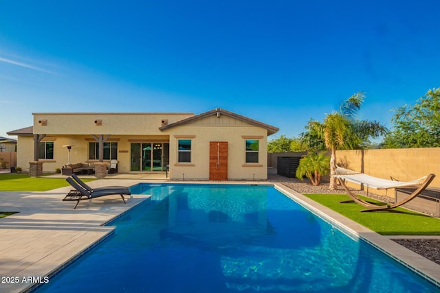back of property with a fenced backyard, a fenced in pool, a patio, and stucco siding