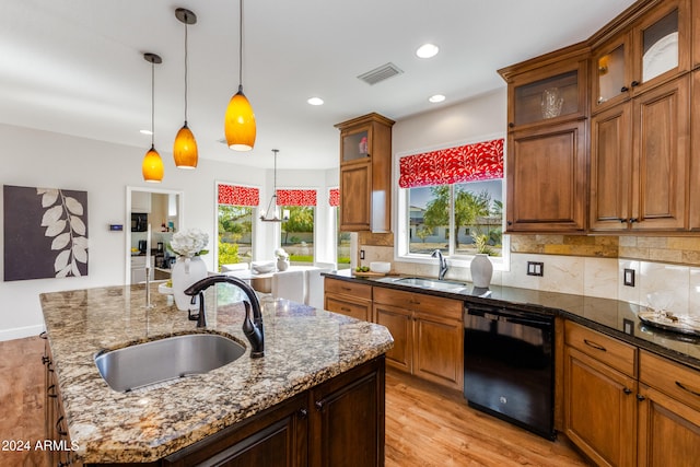 kitchen featuring a wealth of natural light, black dishwasher, a kitchen island with sink, and pendant lighting