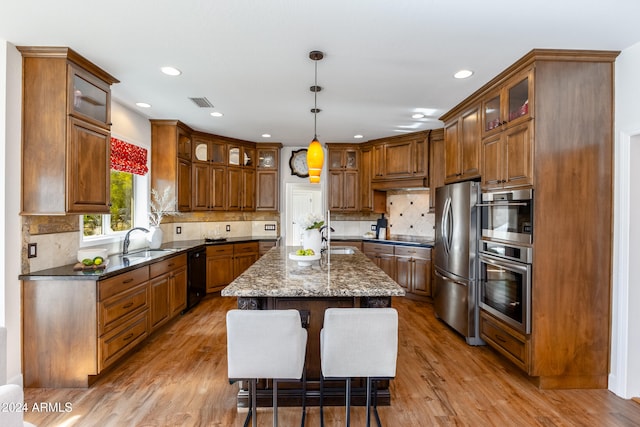 kitchen with a center island, appliances with stainless steel finishes, dark stone counters, and light wood-type flooring